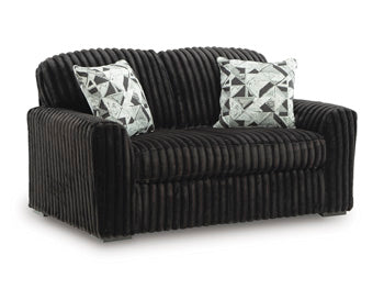 Ashley Furniture Midnight-Madness loveseat with plush dark upholstery and cozy armrests, shown from an angled side view.