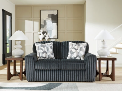 Close-up of the Ashley Furniture Midnight-Madness Loveseat showing plush dark fabric and cushioned armrests.