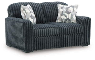 Ashley Furniture Midnight-Madness loveseat shown from an angled side view, featuring dark upholstery and plush cushions.