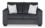 Ashley Furniture Altari loveseat showing plush beige fabric, cushioned backrest, and wooden legs in a cozy living room setting.