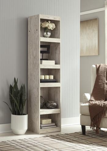 Willowton Pier media tower by Ashley Furniture featuring a modern wooden design with open shelving and storage compartments.