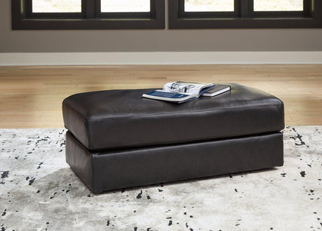 Ashley Furniture Amiata Ottoman in neutral fabric with wooden legs, showcasing a versatile and stylish living room accent piece.