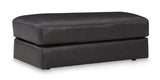 Ashley Furniture Amiata Ottoman featuring a plush fabric top and wooden legs, ideal as a versatile living room accent piece.
