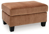Ashley Furniture Amity Bay Ottoman with soft fabric upholstery and wooden legs, shown as a stylish living room accent piece.
