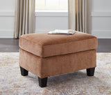 Ashley Furniture Amity Bay Ottoman featuring a cushioned top and wooden legs, ideal for living room or bedroom decor.