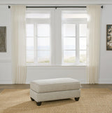 Ashanti ottoman by Ashley Furniture featuring a plush fabric surface and wooden legs, ideal for living room decor.