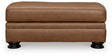 Ashley Furniture Carianna Ottoman with plush fabric and tufted top, shown from a front head-on perspective.