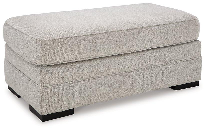Eastonbridge Ottoman by Ashley Furniture, showing a stylish upholstered ottoman with wooden legs in a home living space.