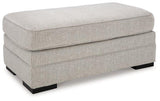 Eastonbridge Ottoman by Ashley Furniture, showing a stylish upholstered ottoman with wooden legs in a home living space.