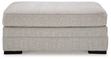 Ashley Furniture Eastonbridge Ottoman featuring a plush cushioned top and wooden legs, perfect for living room decor.