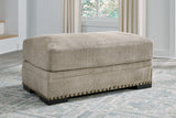 Ashley Furniture Galemore Ottoman with plush fabric and wooden legs, shown in a cozy living room setting.