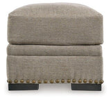 Ashley Furniture Galemore Ottoman with plush fabric and wooden legs, serving as a stylish, functional accent piece in a living room.