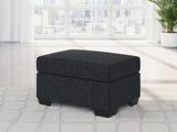 Ashley Furniture Jasmine Peaks Ottoman with upholstered fabric and wooden legs, showcasing a stylish and functional living room accent piece.