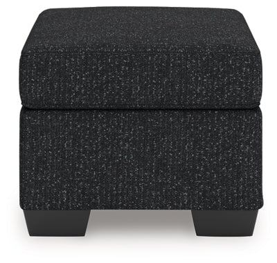 Ashley Furniture Jasmine Peaks Ottoman with fabric upholstery and wooden legs, shown from a side view.