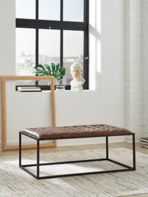 Ashley Furniture Junsor coffee table ottoman with tufted fabric top and wooden legs, versatile living room accent piece.