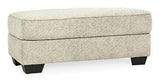 Ashley Furniture Monaghan Ottoman with plush fabric and wooden legs, designed for versatile seating and interior decor.