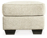 Ashley Furniture Monaghan Ottoman with plush fabric and wooden legs, showcasing its stylish and versatile design.