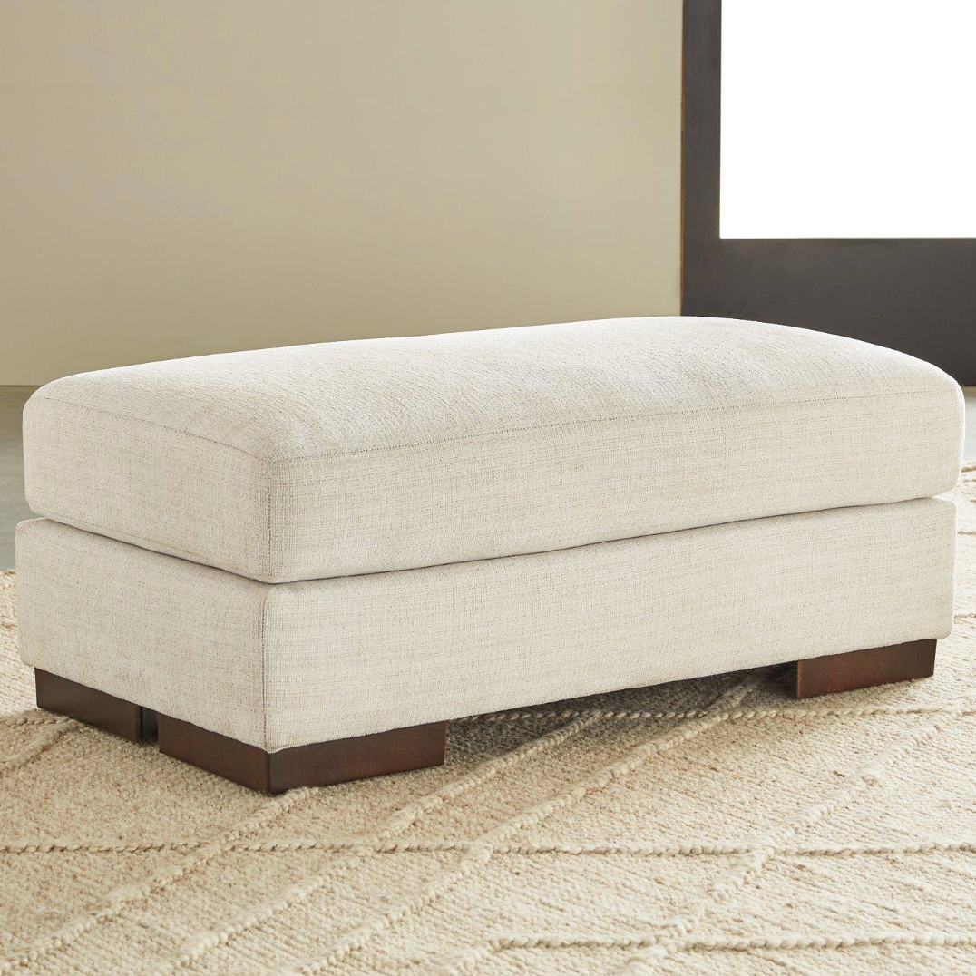 Ashley Furniture Newport Ottoman, cushioned fabric ottoman with wooden legs, provides versatile seating and stylish decor.