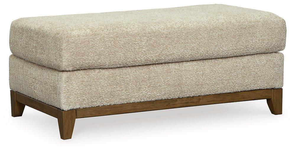 Ashley Furniture Parklynn Ottoman showing a plush, upholstered fabric with a simple, elegant design suitable for living room decor.