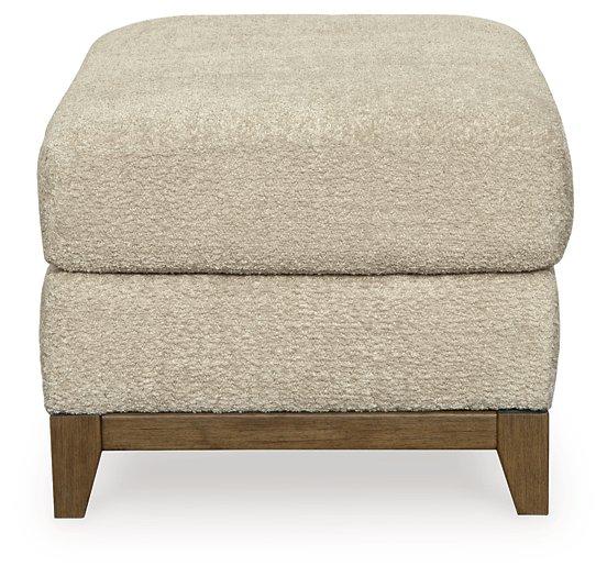 Ashley Furniture Parklynn Ottoman showing soft fabric upholstery and wooden legs in a cozy living room setting.