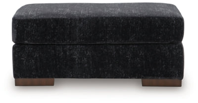 Ashley Furniture Whitmore Manor Ottoman with plush fabric and wooden legs, shown from a head-on angle.