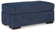 Ashley Furniture Evansley Ottoman showing a plush fabric surface and wooden legs, ideal for living room or bedroom decor.