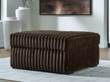 Ashley Furniture Midnight-Madness oversized accent ottoman with plush fabric and wooden legs, shown in a cozy living room setting.