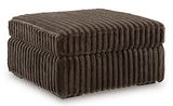 Oversized Ashley Furniture Midnight-Madness accent ottoman with plush fabric and a modern design, shown from an angled view.