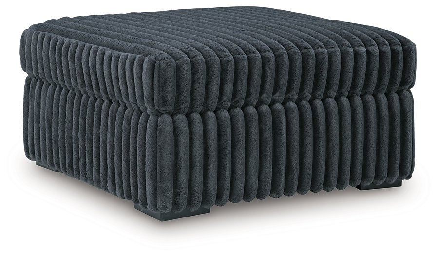 Ashley Furniture Midnight-Madness oversized accent ottoman with plush fabric and sturdy wooden legs, shown from an angled view.