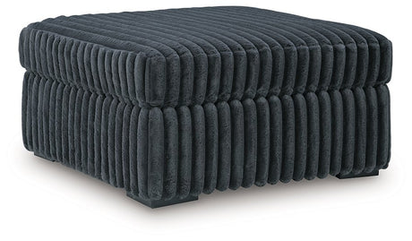 Ashley Furniture Midnight-Madness oversized accent ottoman with plush fabric and sturdy wooden legs, shown from an angled view.