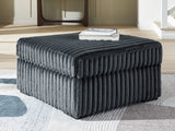 Ashley Furniture Midnight-Madness oversized accent ottoman with plush fabric and decorative stitching, shown in a modern living room setting.