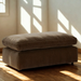 Sand-colored Ashley Furniture Nova Cloud Ottoman with soft fabric upholstery and a modern, plush design.