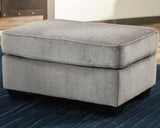 Ashley Furniture Altari Ottoman showing a plush, upholstered ottoman with a neutral fabric finish and stylish wooden legs.