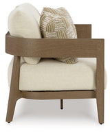 Outdoor loveseat with cushions by Ashley Furniture, shown with plush seating and supportive armrests in a serene outdoor setting.