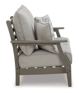 Outdoor Ashley Furniture Visola loveseat and coffee table set with cushioned seating and wooden coffee table in a garden setting