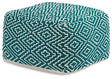Ashley Furniture Brynnsen pouf with soft fabric upholstery and a modern round design, shown from an angled side view.