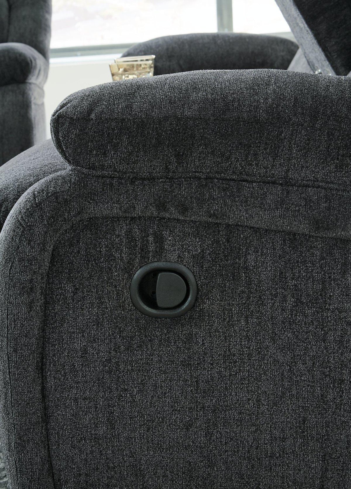 Ashley Furniture Draycoll recliner showing plush fabric, padded armrests, and a comfortable reclining position in a modern living room setting.