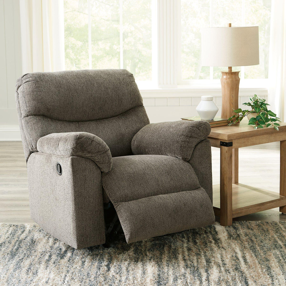 Comfortable Ashley Alphons Recliner with plush fabric and padded armrests, designed for relaxation and style.