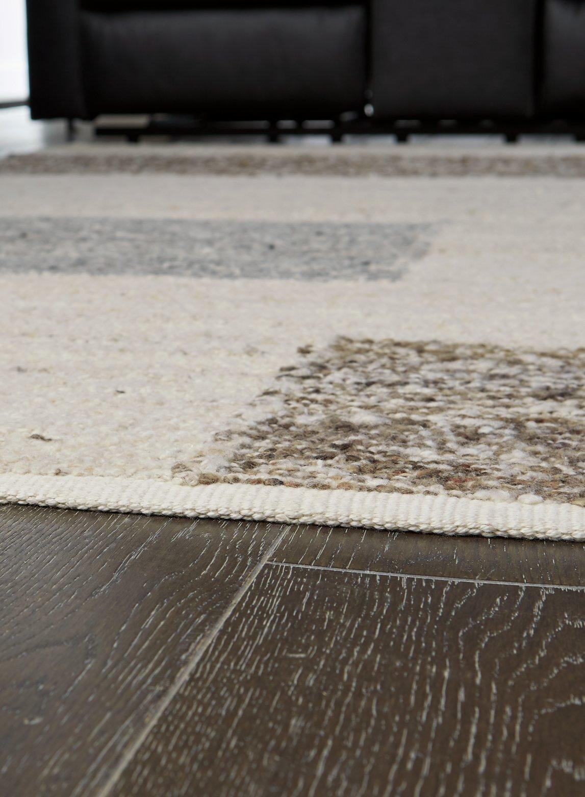 Ashley Furniture Barus Rug with intricate patterns and warm colors, showcasing a soft, woven surface ideal for living room decor.