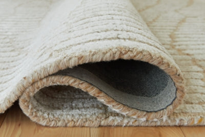 Close-up of Ashley Furniture Jaseena area rug showing intricate woven pattern and soft texture in neutral tones.