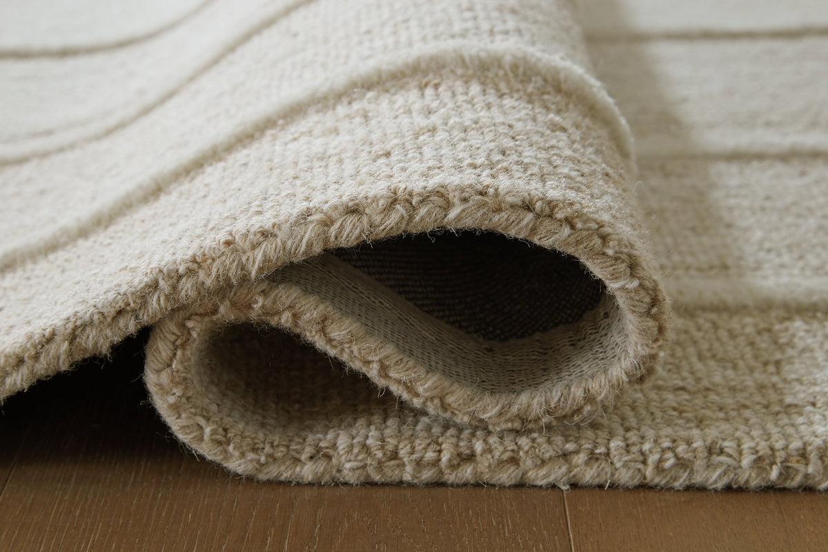Close-up of a Teelgan Rug by Ashley Furniture showing detailed woven pattern and soft texture on a neutral background.