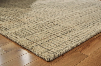 Close-up of the Ashley Furniture Janston Rug showing intricate patterns and soft textures in neutral tones.