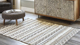 Ashley Furniture Karalee 8' x 10' rug with intricate patterns in neutral tones, shown laid out on a hardwood floor.