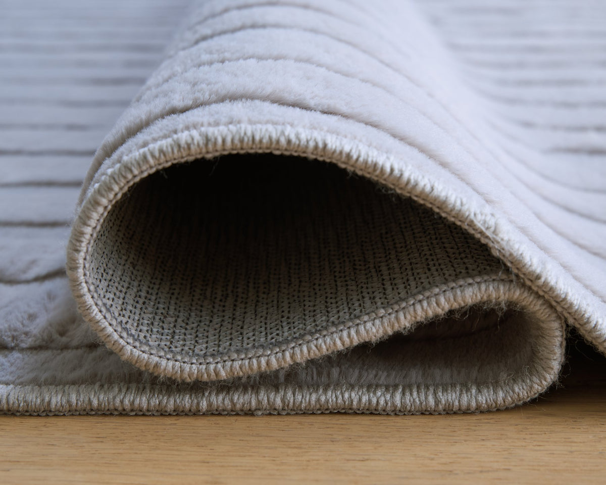 Medium washable area rug by Ashley Furniture with intricate pattern and soft texture, shown in detailed close-up image.