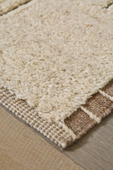 Close-up of Ashley Furniture Clayman Rug showing textured beige and brown woven pattern and soft fabric fibers.