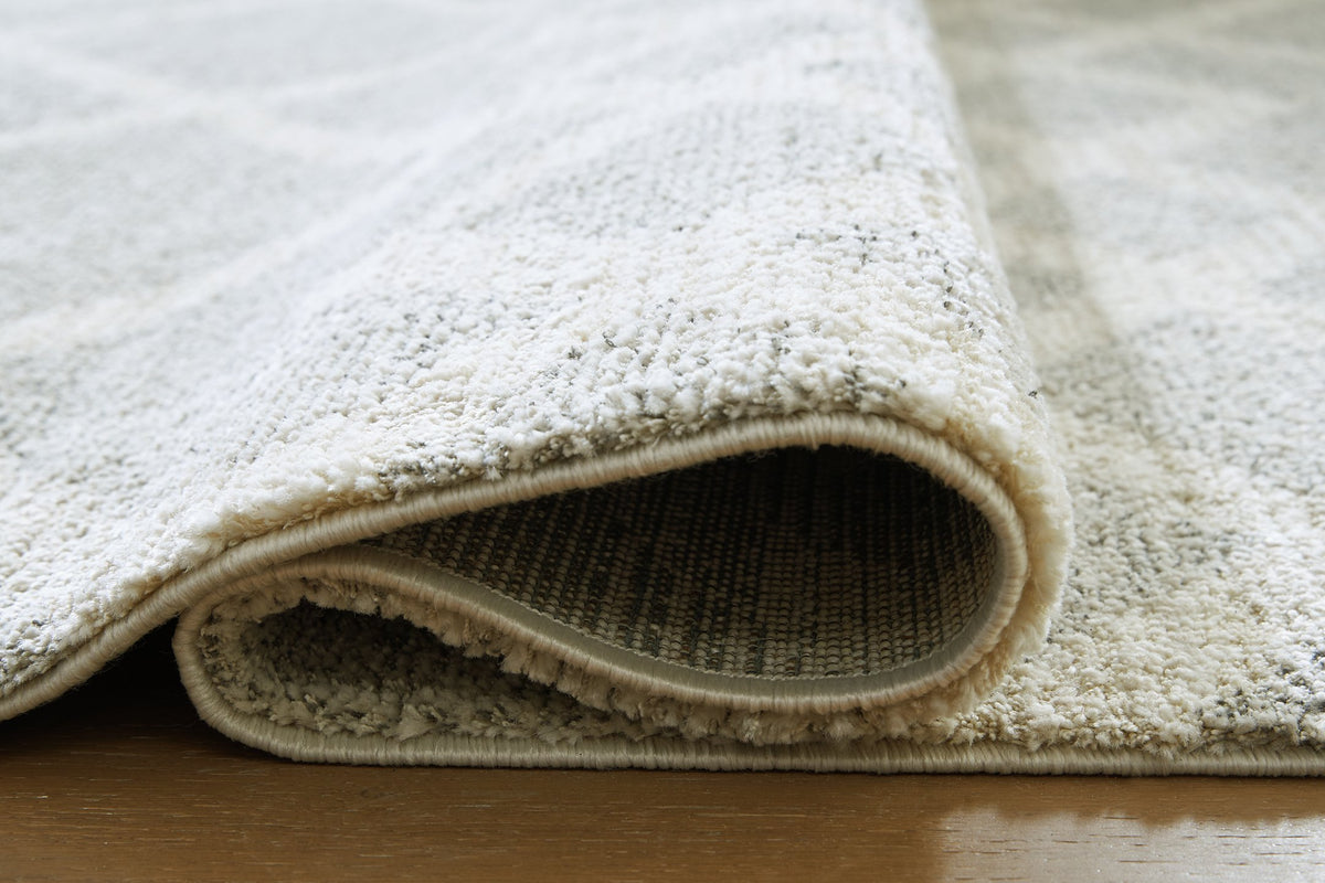 Medium Ashley Furniture Unawick Rug with detailed woven texture, showcasing soft, neutral-toned fibers and intricate design.