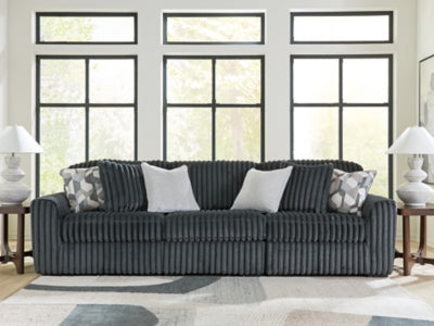 Ashley Furniture Midnight-Madness sectional sofa with dark fabric, featuring multiple seating sections and plush cushions.