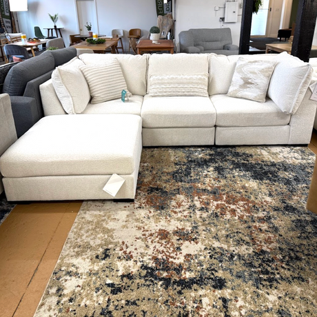 Ashley Furniture Pebblebrook 3-piece sectional sofa with ottoman, featuring plush fabric and modern design, shown in a living room setting.