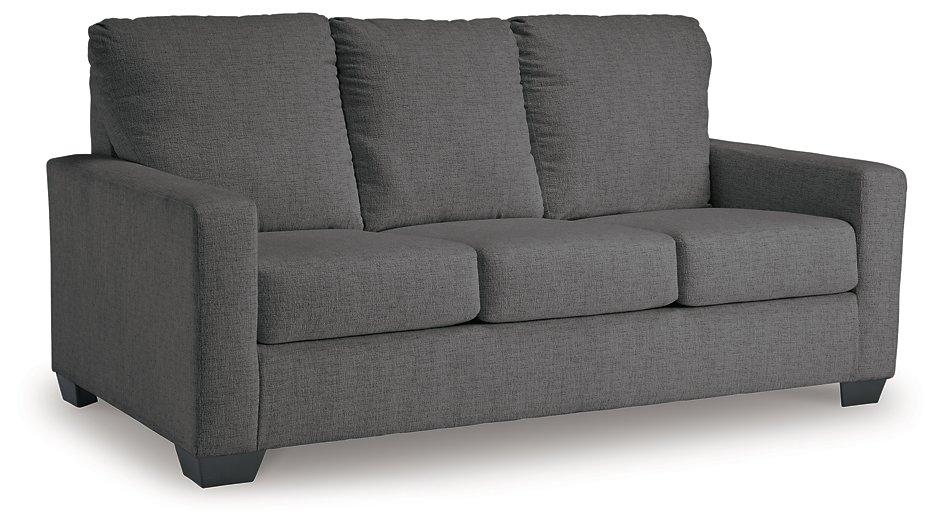 Ashley Furniture Rannis sofa sleeper with beige fabric and wooden legs, shown in a stylish living room setting.
