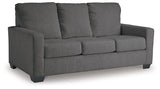 Ashley Furniture Rannis sofa sleeper with beige fabric and wooden legs, shown in a stylish living room setting.